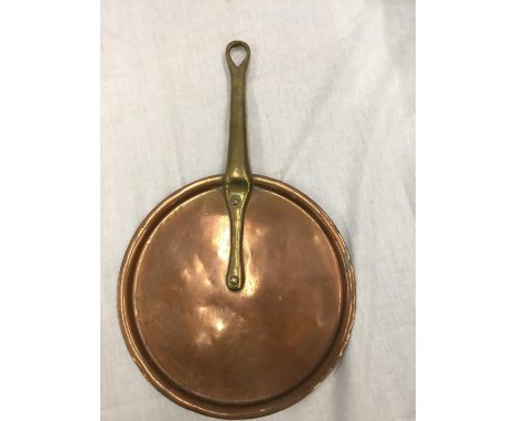 A VINTAGE COPPER SKILLET WITH A BRASS HANDLE 