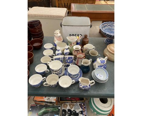 AN ASSORTMENT OF ITEMS TO INCLUDE AN ENAMEL BREAD BIN, CERAMIC JUGS AND BLUE AND WHITE CUPS AND SAUCERS ETC 