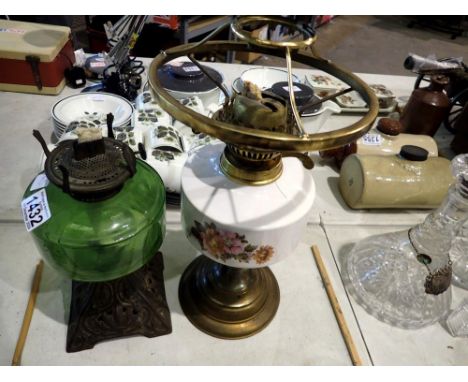 Two oil lamps, one ceramic floral patterned and one with a green glass reservoir and Art Nouveau metal base. Not available fo