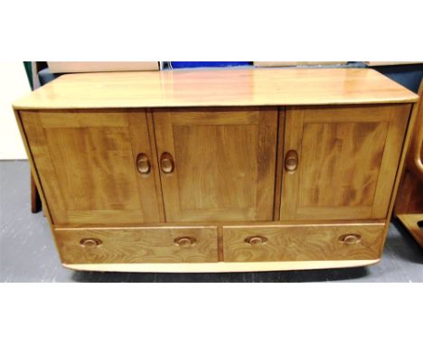 AN ERCOL LIGHT ELM SIDEBOARD  with pair of doors and single door above two drawers, casters to base, 130cm long 50cm deep 77c