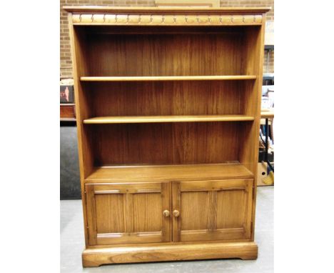 AN ERCOL 'GOLDEN DAWN' BOOKCASE  with two adjustable shelves above cupboard, 101cm wide 31cm deep 138cm high