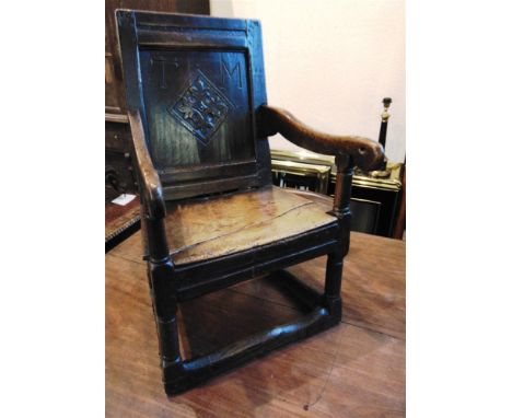 AN OAK WAINSCOT CHAIR  the back panel carved with a lozenge and initials 'T M', fruitwood seat, turned supports with stretche