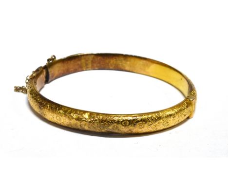 A LATE VICTORIAN FOLIATE ENGRAVED GOLD HOLLOW HINGED BANGLE of 'D' section (repair), with a plain push-snap, stamped '15c', a