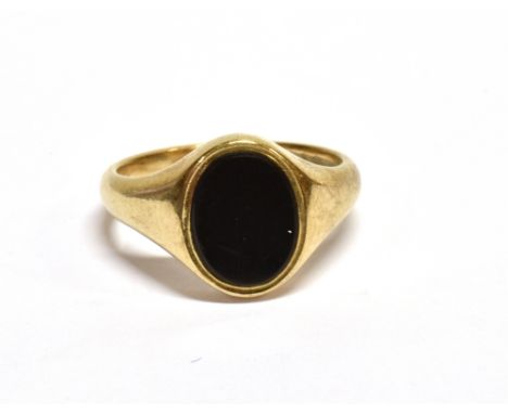 A VINTAGE 9CT GOLD AND BLACK ONYX OVAL SIGNET RING the black onyx flat-oval panel flush-set to a tapering shank, marks indist