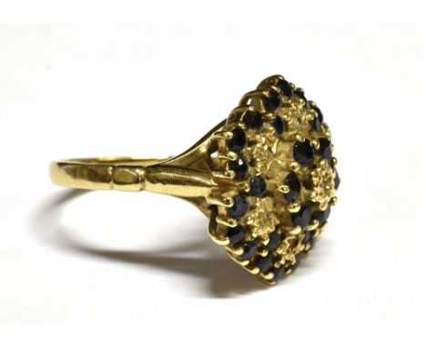 A VINTAGE 9CT GOLD, SAPPHIRE AND DIAMOND FLOWER-HEAD CLUSTER RING of hexagonal outline, set with 30 small very dark sapphires