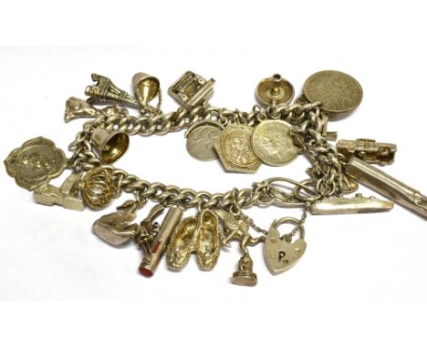 A VINTAGE SILVER CURB LINK 'CHARM' BRACELET on a padlock clasp and hung with 26 various charms including a spinning wheel, a 