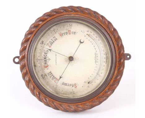 A LATE 19th CENTURY SILVERED DIAL ANEROID BAROMETER with curved thermometer enclosed with oak rope edge surround 28cm diamete