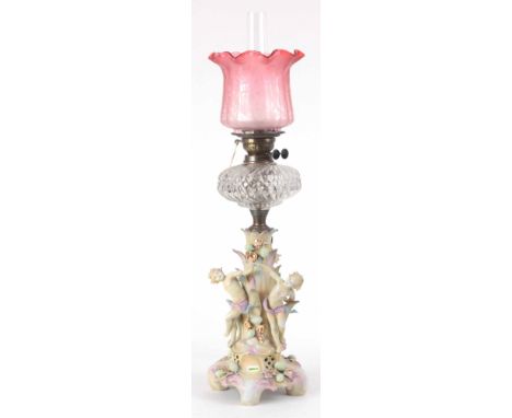 A 19th CENTURY OIL LAMP WITH PORCELAIN BASE WITH CHILDREN DANCING AND AN ETCHED CRANBERRY GLASS SHADE 82cm high