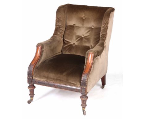 A LATE 19TH CENTURY OAK FRAMED ARMCHAIR with winged sides and button back, on a leaf carved frame with tapering turned legs o
