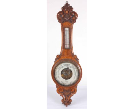 AN EARLY 20th CENTURY WALL ANEROID BAROMETER AND THERMOMETER IN A CARVED OAK CASE 90cm high