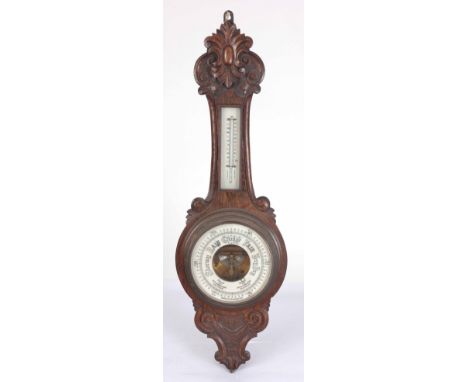 AN EARLY 20th CENTURY WALL ANEROID BAROMETER AND THERMOMETER IN A CARVED OAK CASE 91cm high