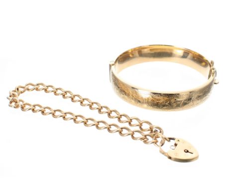 9ct bangle with stylised foliate engraved decoration, 17.2gm; also a 9ct curb bracelet with a padlock clasp, 19gm, 8" long