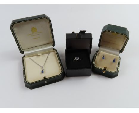 A suite of white gold tanzanite jewellery comprising a pendant and chain, a pair of earrings and a ring. The pendant with a p