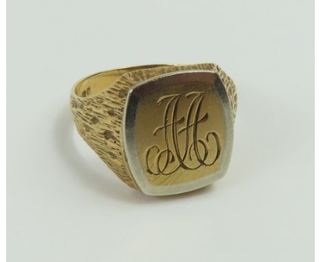 A 9ct gold signet ring, with white gold accent around the edge of the head, monogram AA to head, bark effect shoulders, finge