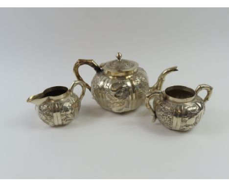 A 20th century Chinese white metal tea set, comprising a teapot, milk jug and two handled sucrier, all decorated with dragons
