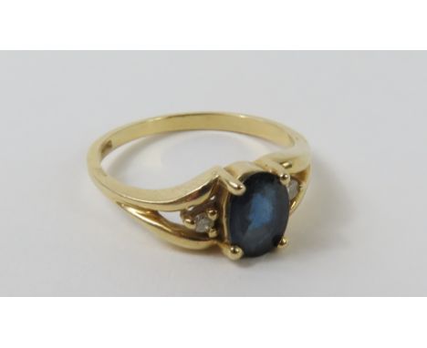 A sapphire dress ring, with a diamond accent to each side, with split shoulders, finger size L, marked '14k', 2.43g gross