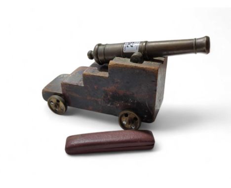 A model of a cannon, the bronze cannon mounted on wood carriage with metal wheels together with two gold metal cased propelli
