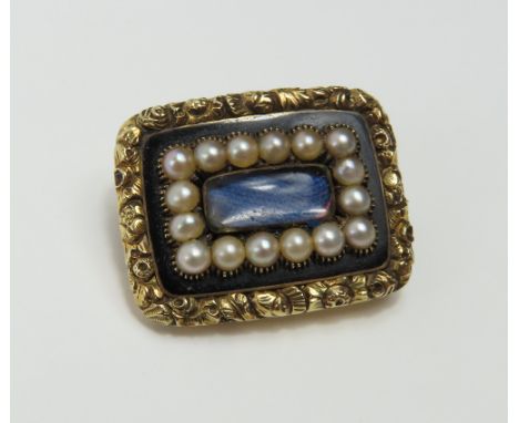 An early 19th century mourning brooch, the slim central hair locket panel surrounded by a row of split pearls, black enamel a