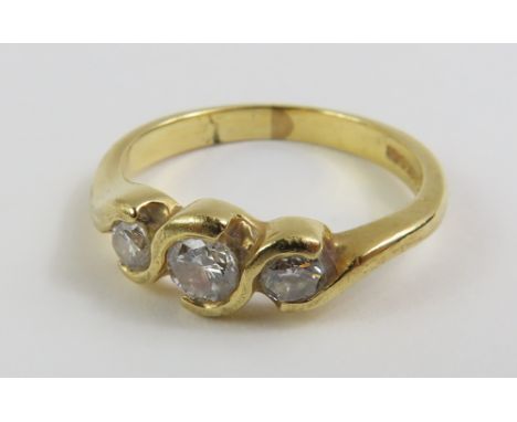 An 18ct gold diamond three stone ring, the three round brilliant cut stones in a twisted semi rub-over setting, the centre st