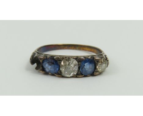 An early 20th century carved head ring, set with two sapphires and two old cut diamonds, with patterned shoulders, finger siz