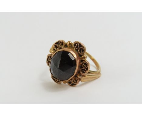 A garnet single stone ring, the stone facetted across the table, in a decorative mount, finger size K, tests as approximately