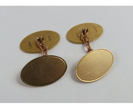 A pair of 9ct gold cufflinks, composed of two oval panels with chain link connectors, one panel engine turned and the other p