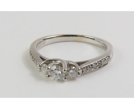 An 18ct white gold diamond three stone ring with diamond set shoulders, finger size K, marked '0.33ct' to the inside of the b