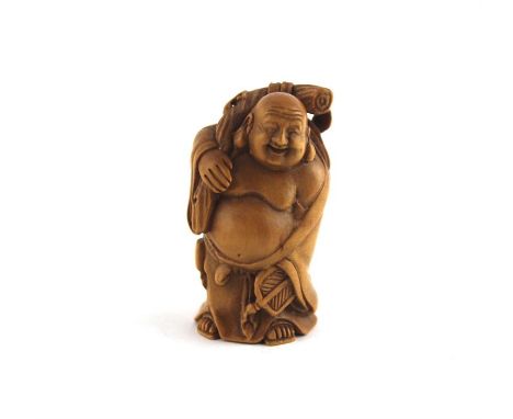 A Japanese Taisho period boxwood netsuke, early 20th century, fashioned as a standing fat bellied Buddha holding staff around