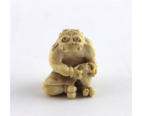 A Japanese Meiji period ivory netsuke/small okimono, late 19th/early 20th century, fashioned as a grotesque creature clutchin