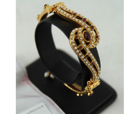 gold coloured Indian style bangle with white and red stones