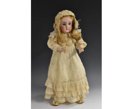 A bisque head doll, fixed pale blue eyes, closed mouth, long blond hair, composite body and limbs, white dress and bonnet, in