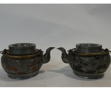 Two Chinese vintage Yixing pottery tea pots with pewter dragon pierced overlays. One with black pottery and one with the icon