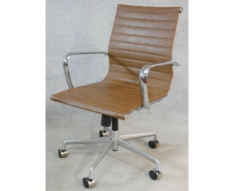 A Charles Eames style swivel office armchair with rise and fall action in light tan leather upholstery. H.90cm 