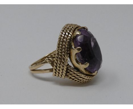 A 9 ct carat yellow gold and amethyst dress ring. Set with an oval mixed cut amethyst in an eight claw open back setting with