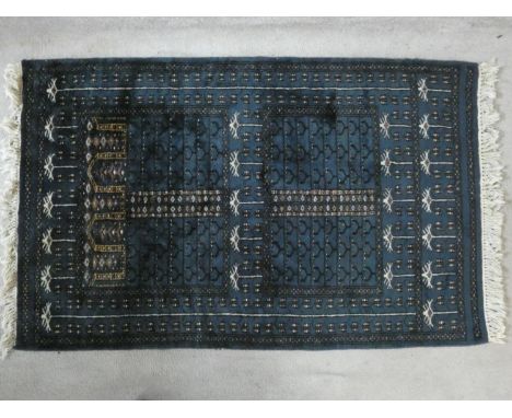 An Eastern rug with repeating floral motifs on an enamel blue ground within geometric border. 92x160cm 