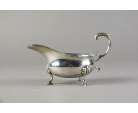 An early 20th century silver sauce boat, Haseler & Bill, Chester 1905, of typical form with cusped rim and raised on three ho