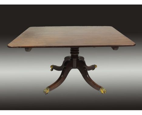 A late Regency mahogany breakfast table, the rectangular tilt top on a compressed baluster turned column and four hipped out-