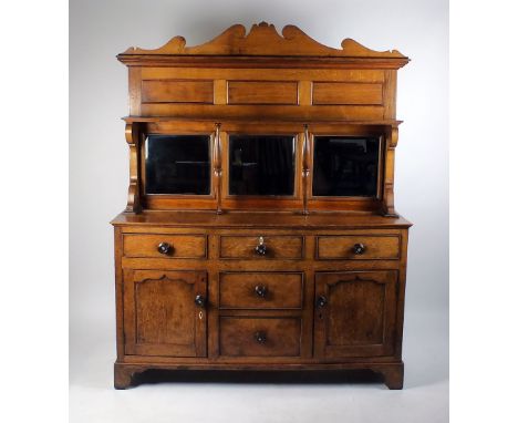 A Victorian oak mirror back side board with cut and shaped panel pediment above a shelf and three mirror panels between brack