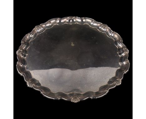 A large George V silver salver, circular form with piecrust edge and cast foliate rim with scrolled feet, by James Dixon & So