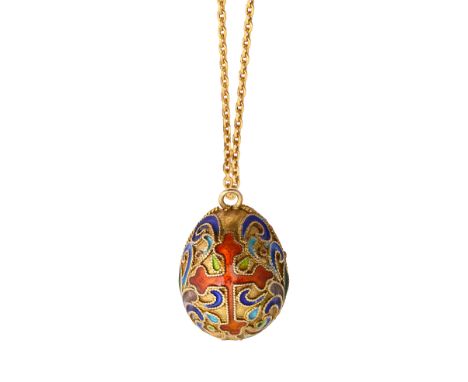 A cloisonne enamel egg pendant with a scrolling design with green, blue and purple enamel, with a central orange enamel cross