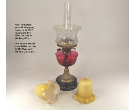 OIL LAMP ETC. A 19th century oil lamp with cranberry glass fount & etched shade, height 60cm. & two small cased glass lampsha