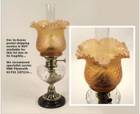 OIL LAMP. A 19th century oil lamp with cut glass reservoir & peach tinted shade. Height 51cm.