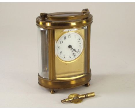 CARRIAGE CLOCK. A French, brass cased oval carriage clock with gilt bezel & key. Height 16cm.