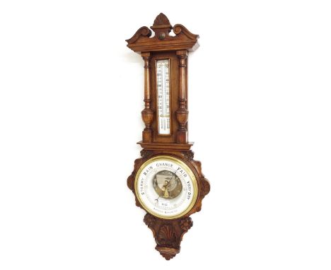Oak cased aneroid barometer/ thermometer, the 8" white chapter ring enclosing a skeletonised centre, under a bevelled glass c