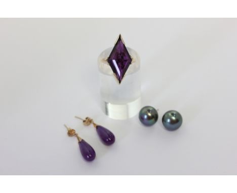 An amethyst dress ring in 9ct gold; a pair of black pearl ear studs on 9ct gold fittings; a pair of purple jade drop earrings