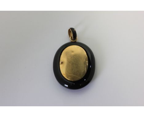 A Victorian black onyx and gold mourning locket on black enamel bale (a/f)