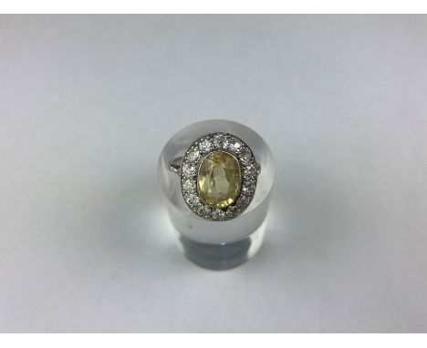 A yellow sapphire and diamond cluster ring, the oval cut stone within a border of old cut diamonds