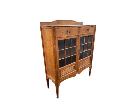 An Arts and Crafts light oak bookcase with later raised back above two drawers with brass back plates and loop handles, and a