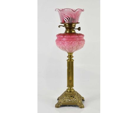 A late Victorian oil lamp, the associated cranberry and milk glass shade with wavy rim above the cranberry and milk glass res