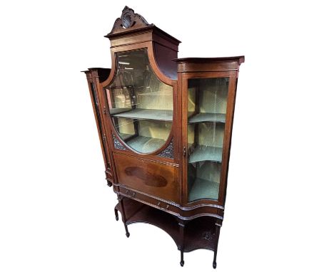 An Edwardian inlaid and carved mahogany display cabinet, the central shield shaped glazed door enclosing single fixed shelf a
